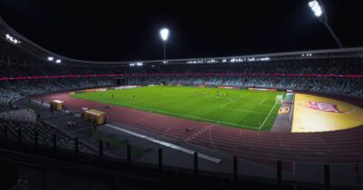 Stade de football illuminé la nuit, pelouse verte sous les projecteurs