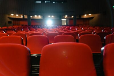 Salle de cinéma, rangées de fauteuils rouges face à l’écran