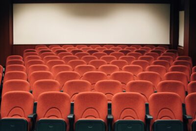 A spacious theater with empty red seats and a large screen, ready for the next audience.